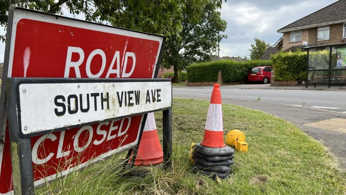 A road closed sign propped up against the South View Avenue road sign