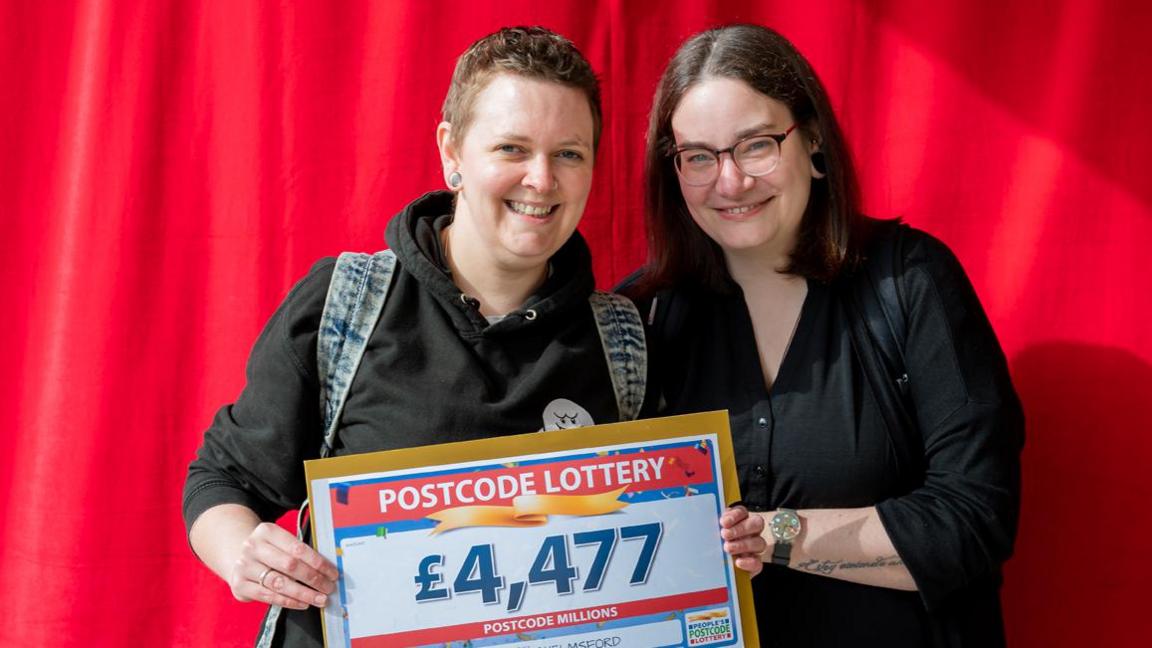 Newlyweds Claire and Kate (left to right) holding a £4,477 cheque