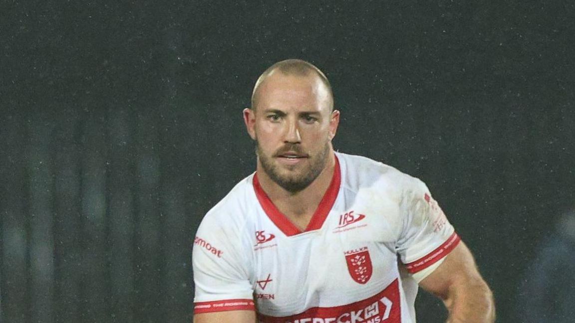 Karl Lawton carrying the ball in both hands but slightly towards his left-hand side playing for Hull KR
