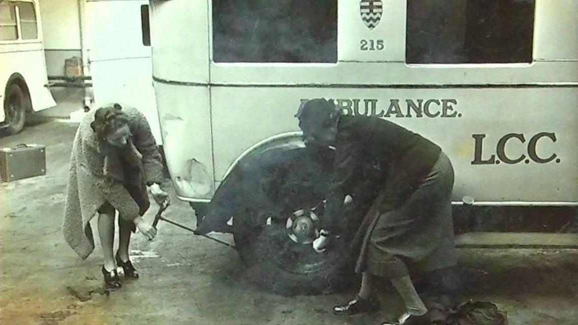 Two women changing a tyre on an ambulance 