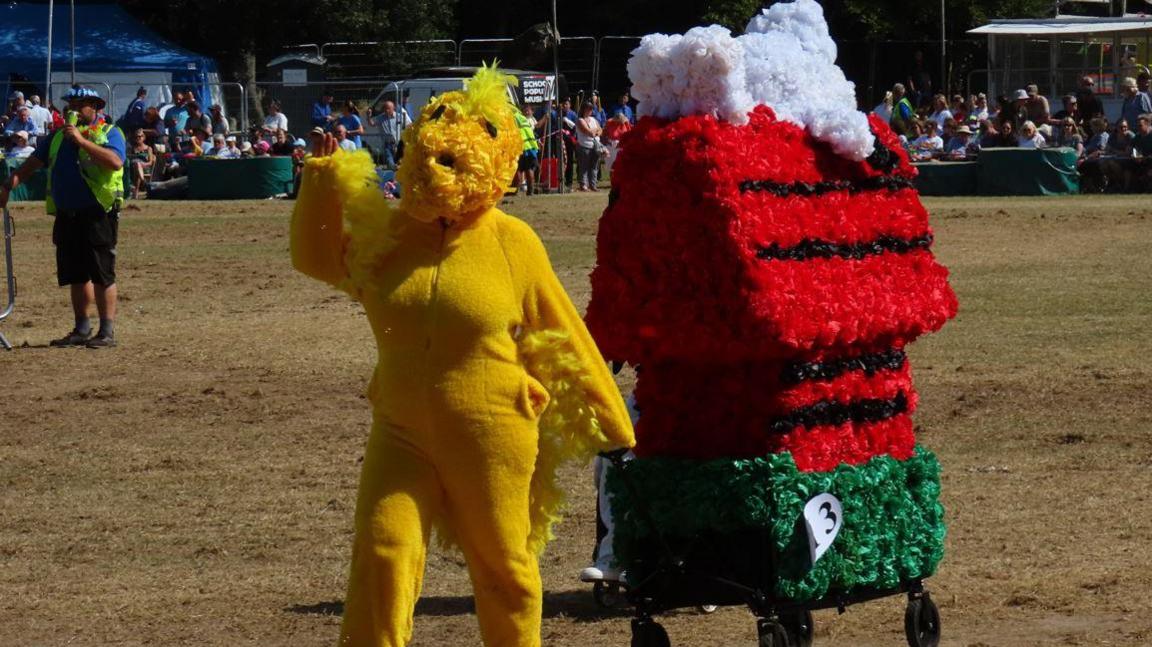 A Battle of Flowers entrant whose design is based on Snoopy and Woodstock from Peanuts. A woman who is part of the display is dressed as Woodstock.