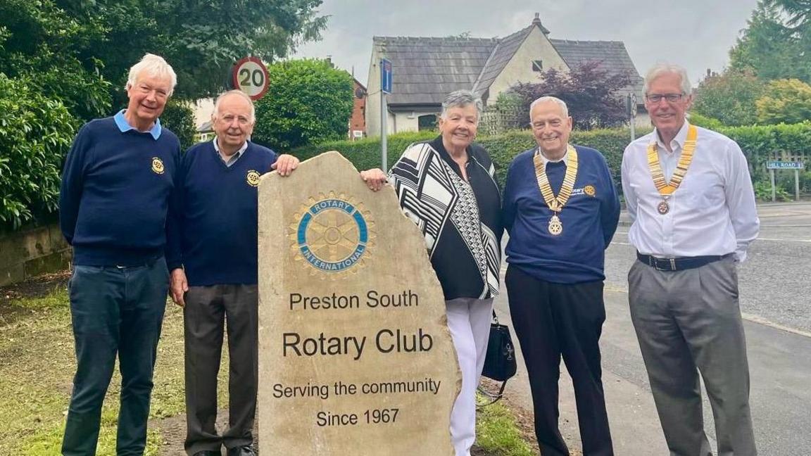 Members of the rotary club stand around the newly installed stone marker on Liverpool Road which reads Preston South Rotary Club - Serving the community since 1967.