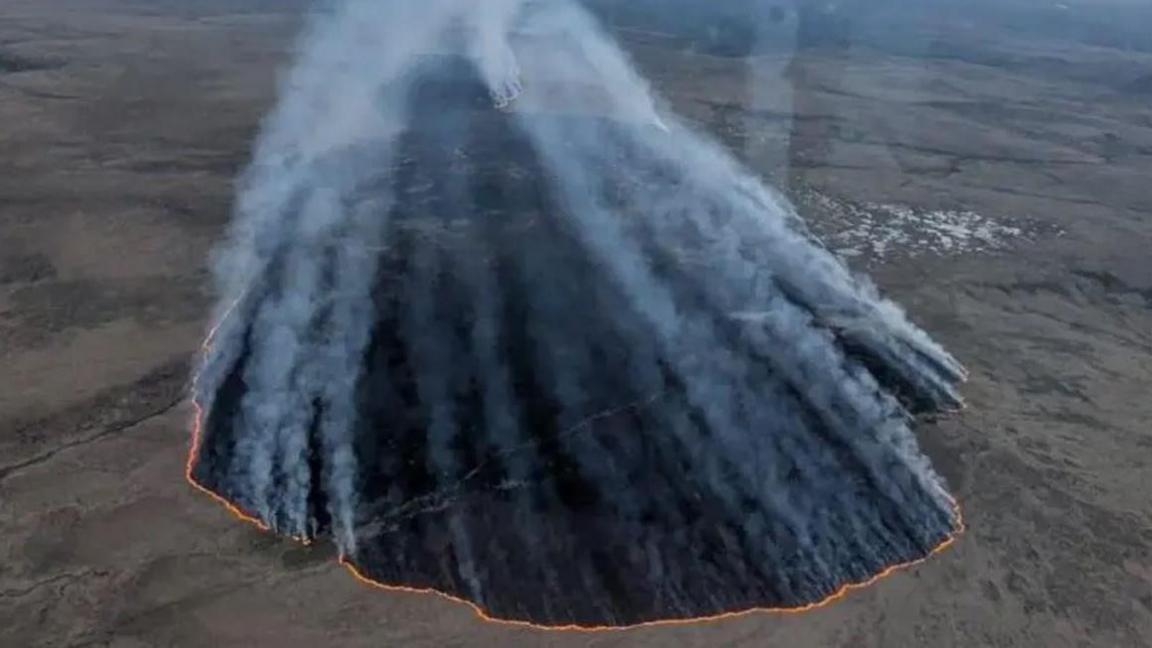 An aerial image showing open plains with a large fire burning through the landscape.
