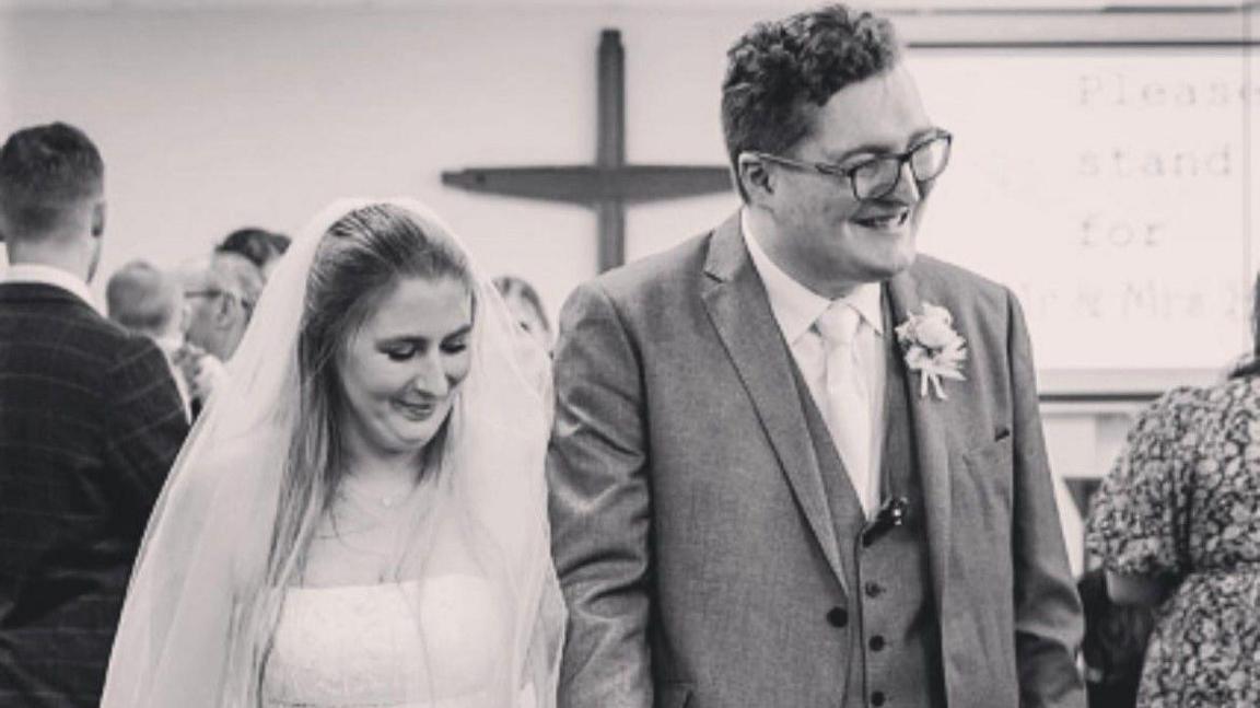 Laura Burr on her wedding day with Ed Burr. She is wearing a wedding dress while he is in a morning suit.