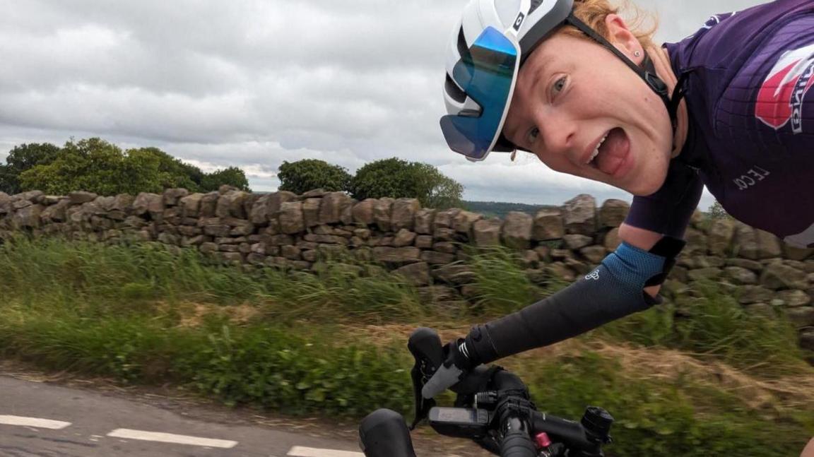 Morgan Newberry cycling on a road wearing a prosthetic arm