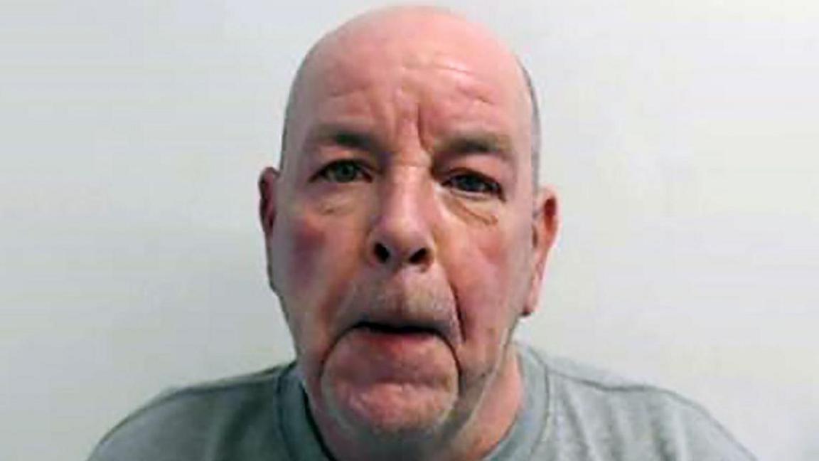 John Higgins, bald with light stubble, head and shoulders police mugshot