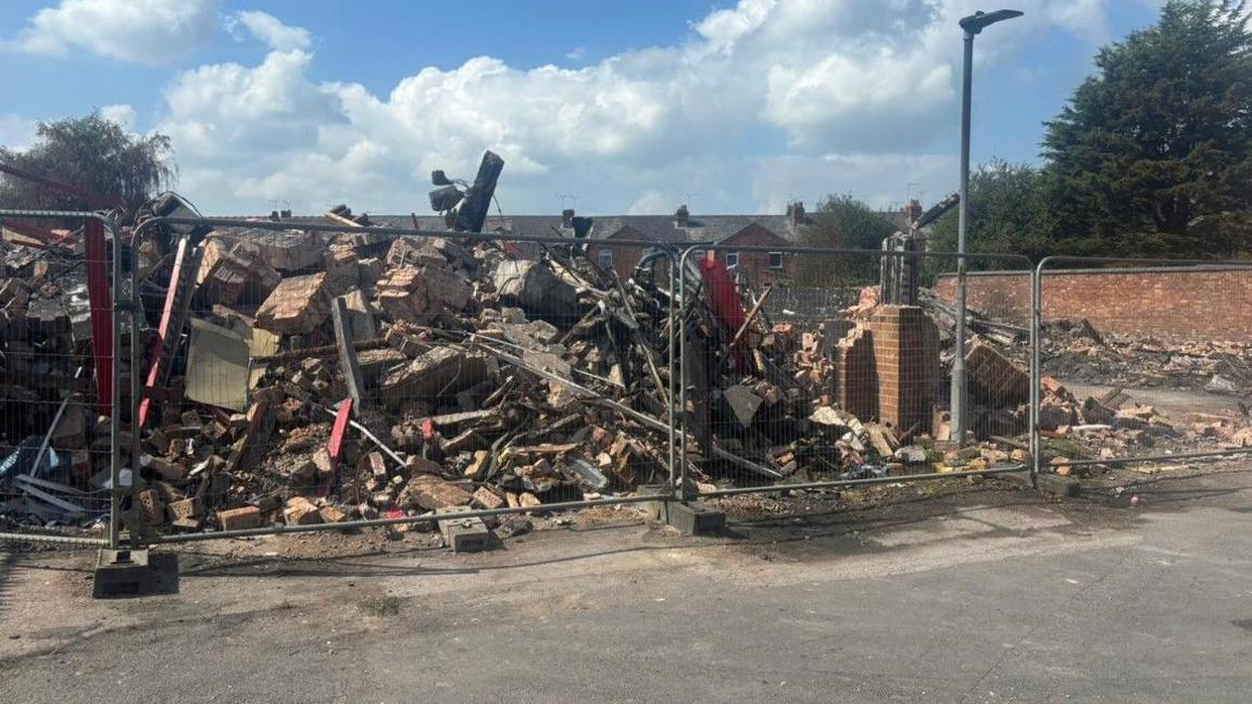 Factory rubble surrounded by metal security fencing.