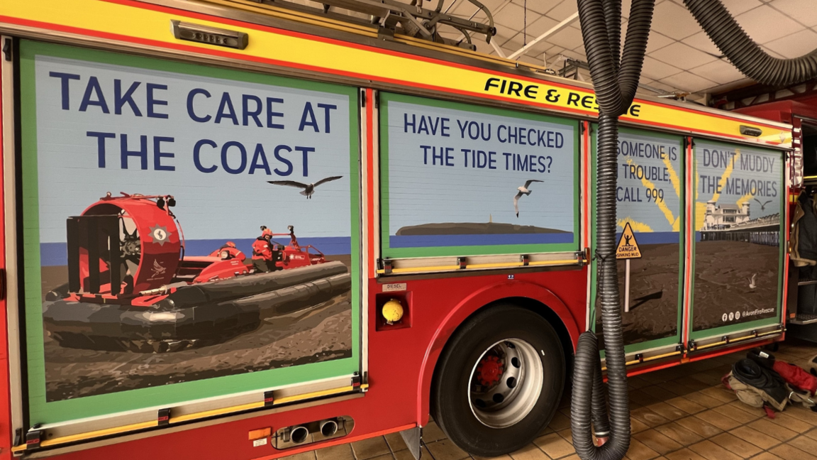 Side of a red fire engine with pictures of coastline with safety messages.