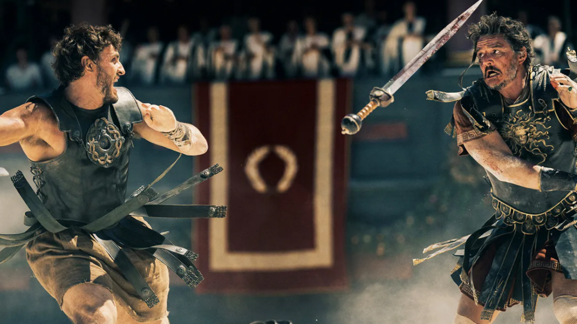 A scene from Gladiator 2, where Paul Mescal left, wearing a Roman Gladiator's uniform fights Pedro Pascal's character. A sword is suspended in the air between them and they both have expression's of stress.  