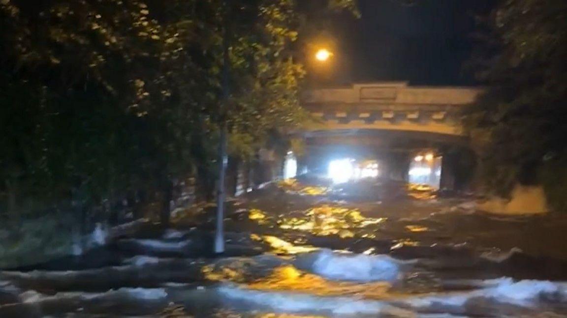 Floodwater churning beneath a railway bridge.