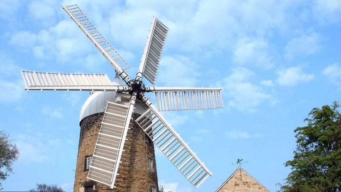 Exterior of Heage Windmill, which has six sails, against a blue sky