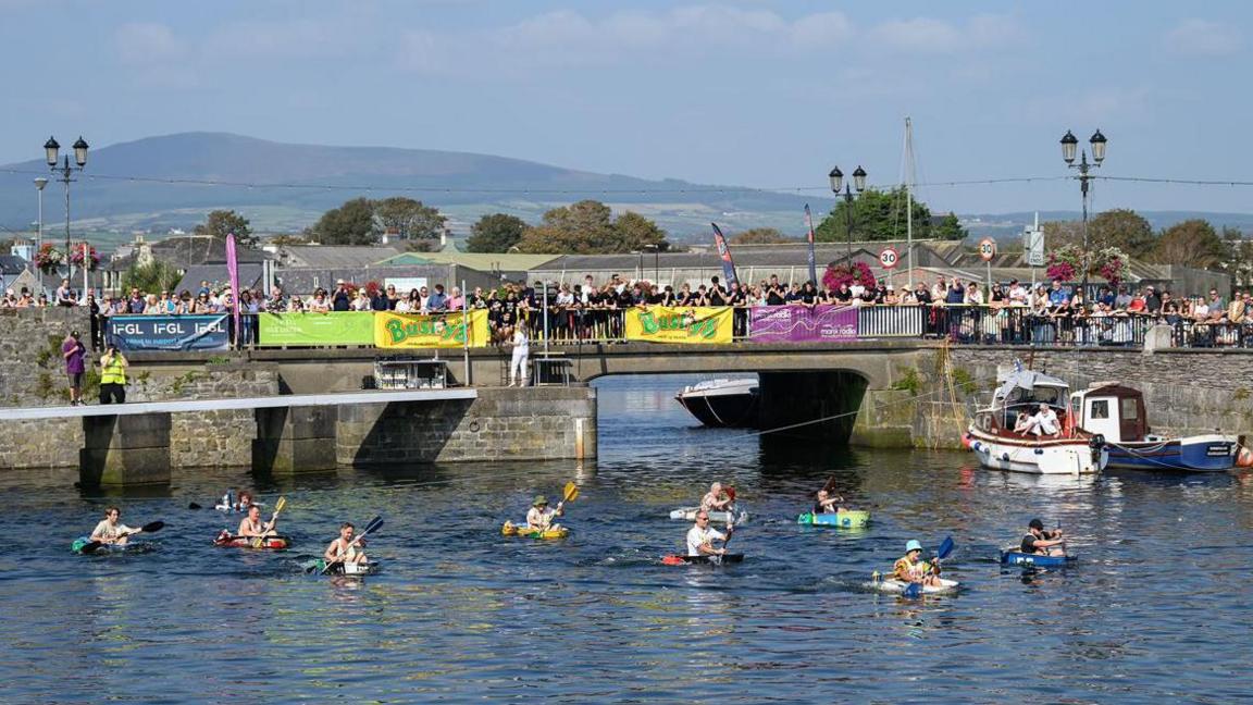 Hundreds of people watch on as the competitors paddle in their tubs in Castletown Harbour.