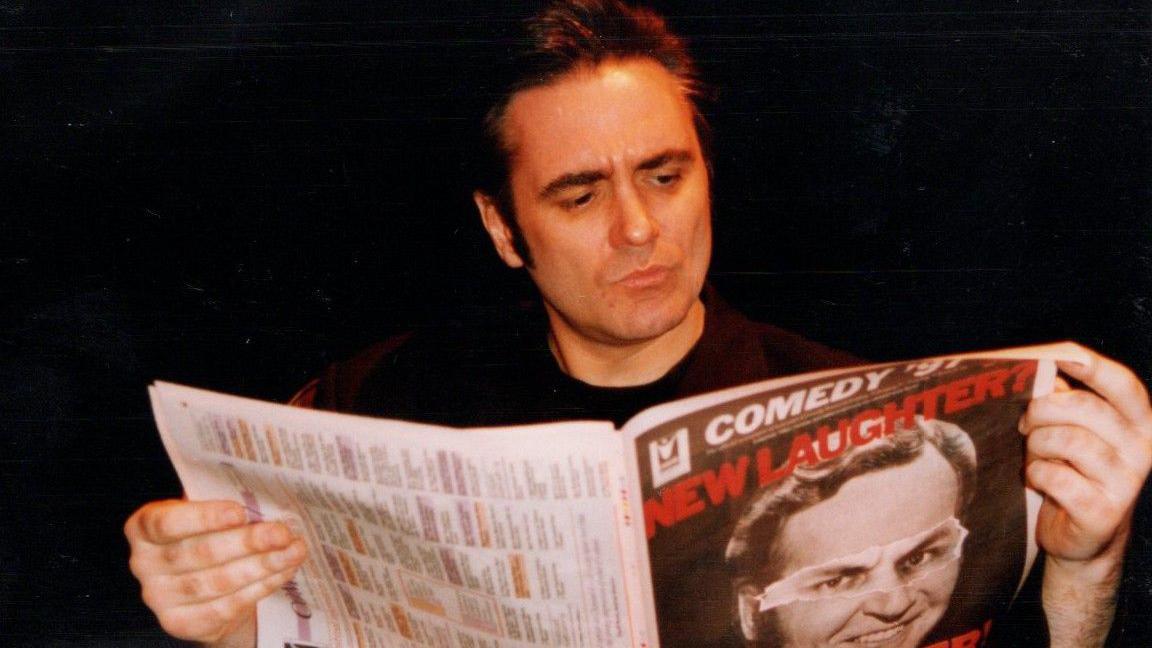 Tony Slattery reading a programme