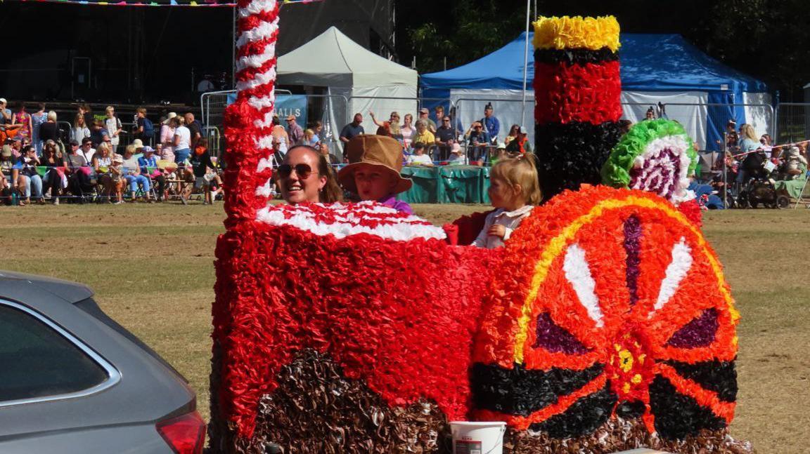 A display made to look like a steamboat with red flowers goes across the showground at the North Park Battle of Flowers.