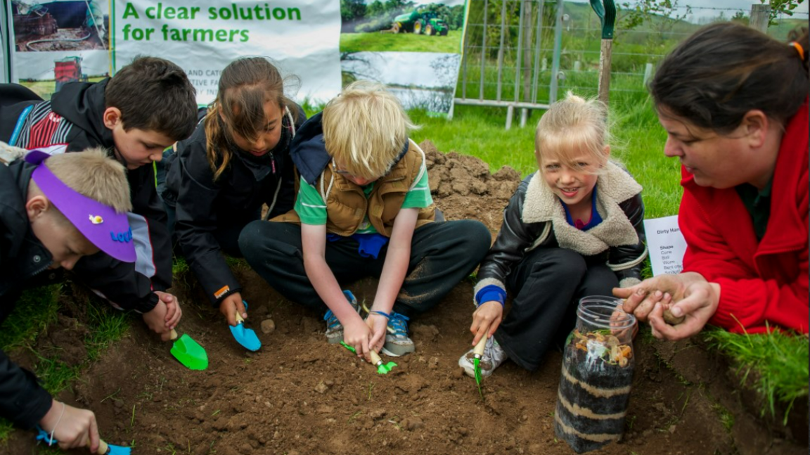 A group of children dig in the soil with trowels