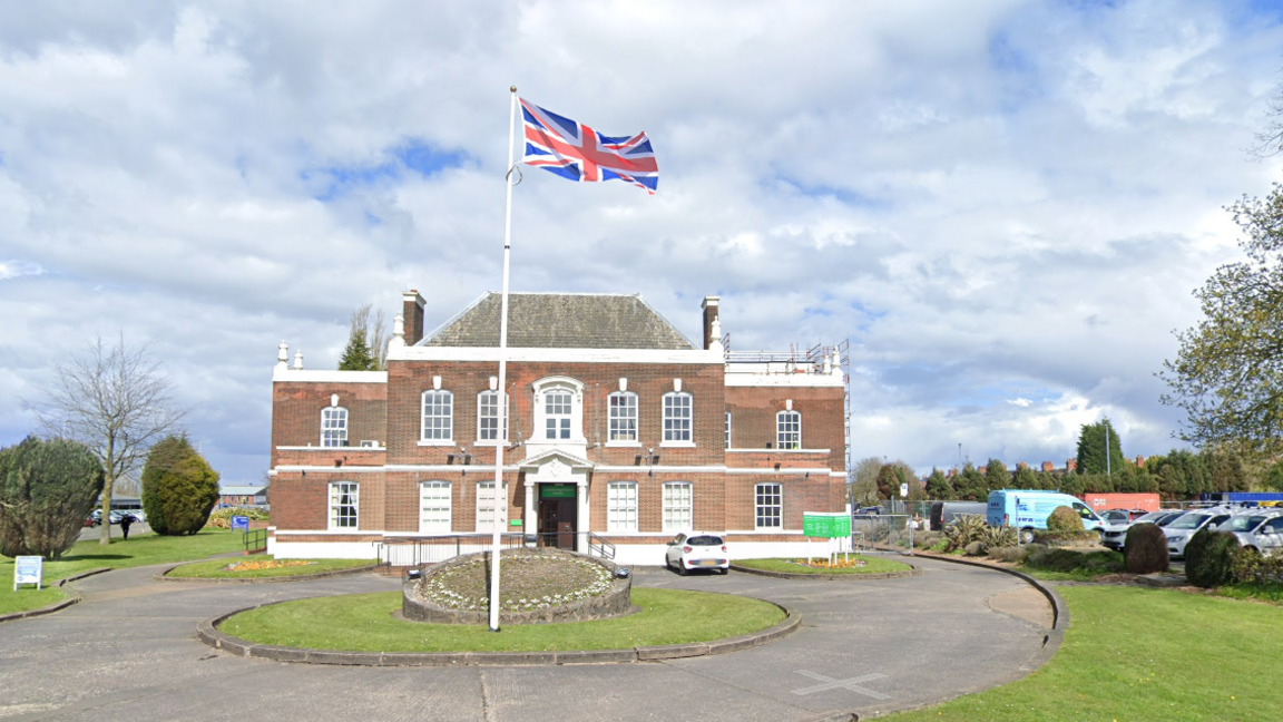 A large civic building with a union flag outside it