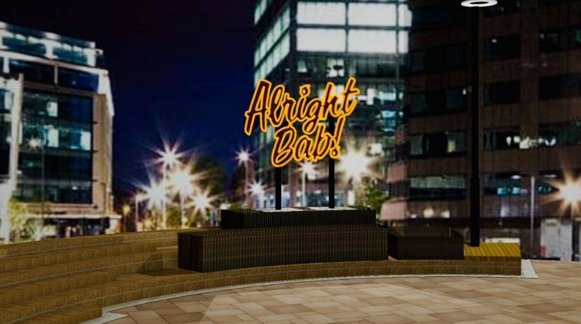 The words Alright Bab! are lit up in Colmore Square. Buildings are blurred in the background of the image at night.