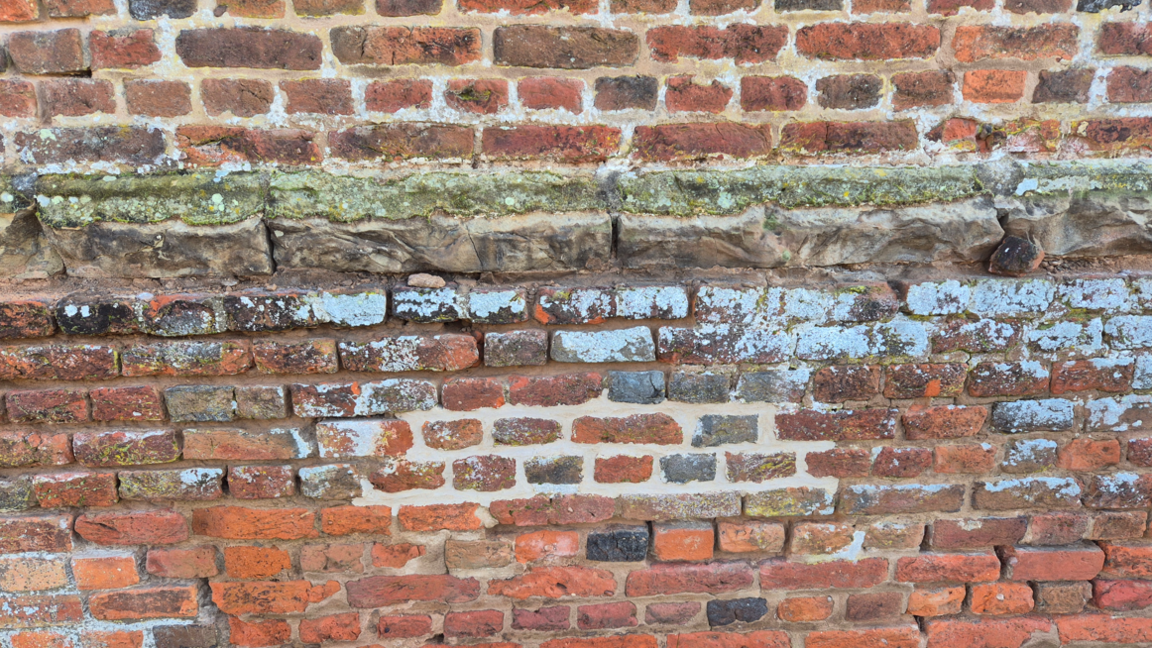 A redbrick wall with fresh mortar in cracks between the bricks