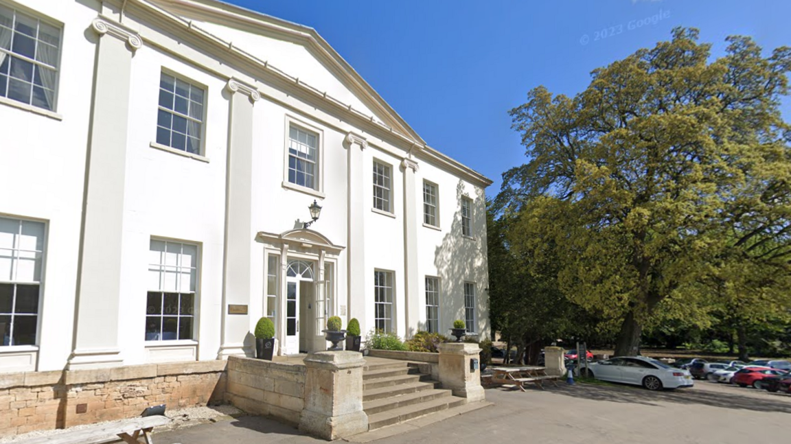 A large white stately home viewed from the car park