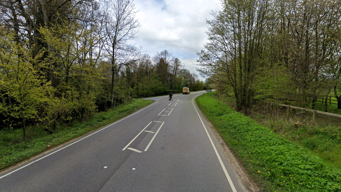 The A1066 at Brettenham showing a motorbike and a van travelling along the road which is lines by trees