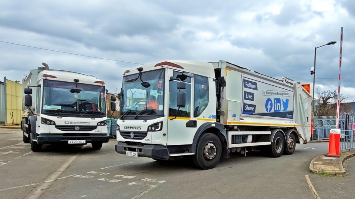 Two white bin lorries in a car park