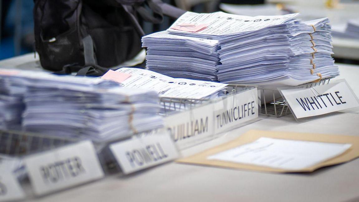 A stack of voting papers are seen next to the name "Whittle"
