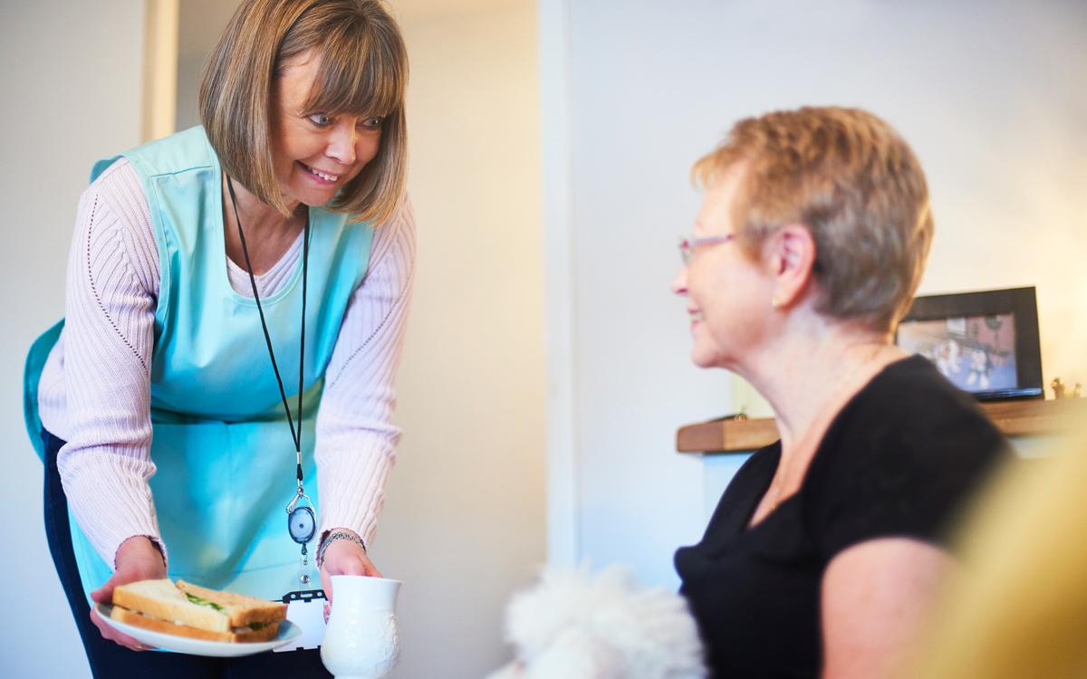 Care worker offers a sandwich to a woman