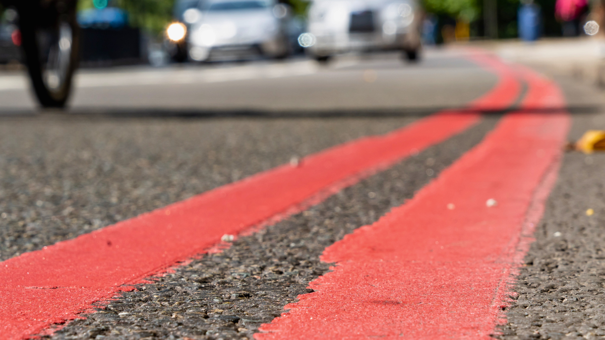 A close up of double red lines painted at the edge of a road.