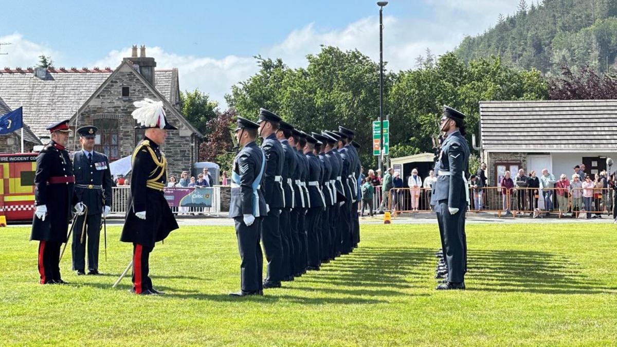 The lieutenant governor in full ceremonial dress standing in front of the Guard of Honour, which is lined up in two rows and standing to attention.