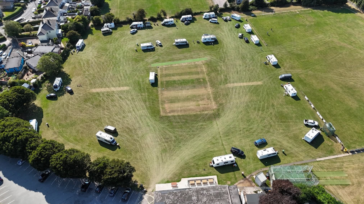 A picture of the vans parked on the large grass field. A number of vans can Be seen parked on the grass in the distance.