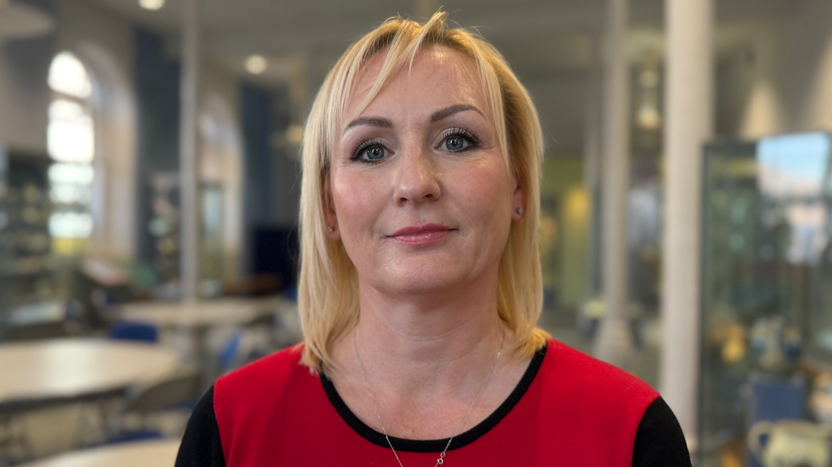 Councillor Beth Jones who has blonde hair and is wearing a red and black dress. The background is blurred.