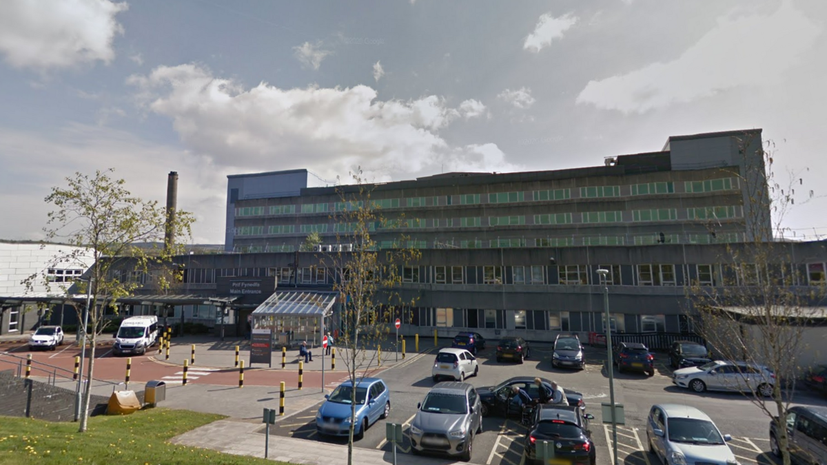 Prince Charles Hospital in Merthyr Tydfil - a large building with several storeys, and with vehicles in a car park at the front