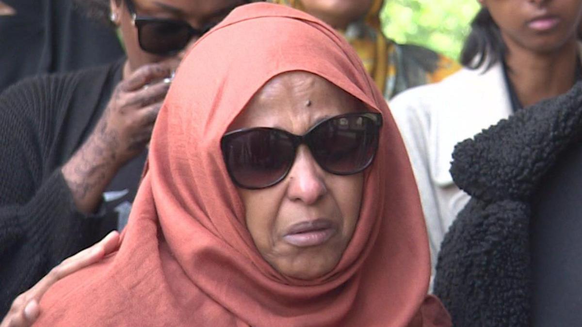 Mr Abdi Mohamed's mother Zahra, who is a Somali woman wearing an orange headscarf and sunglasses. She is crying