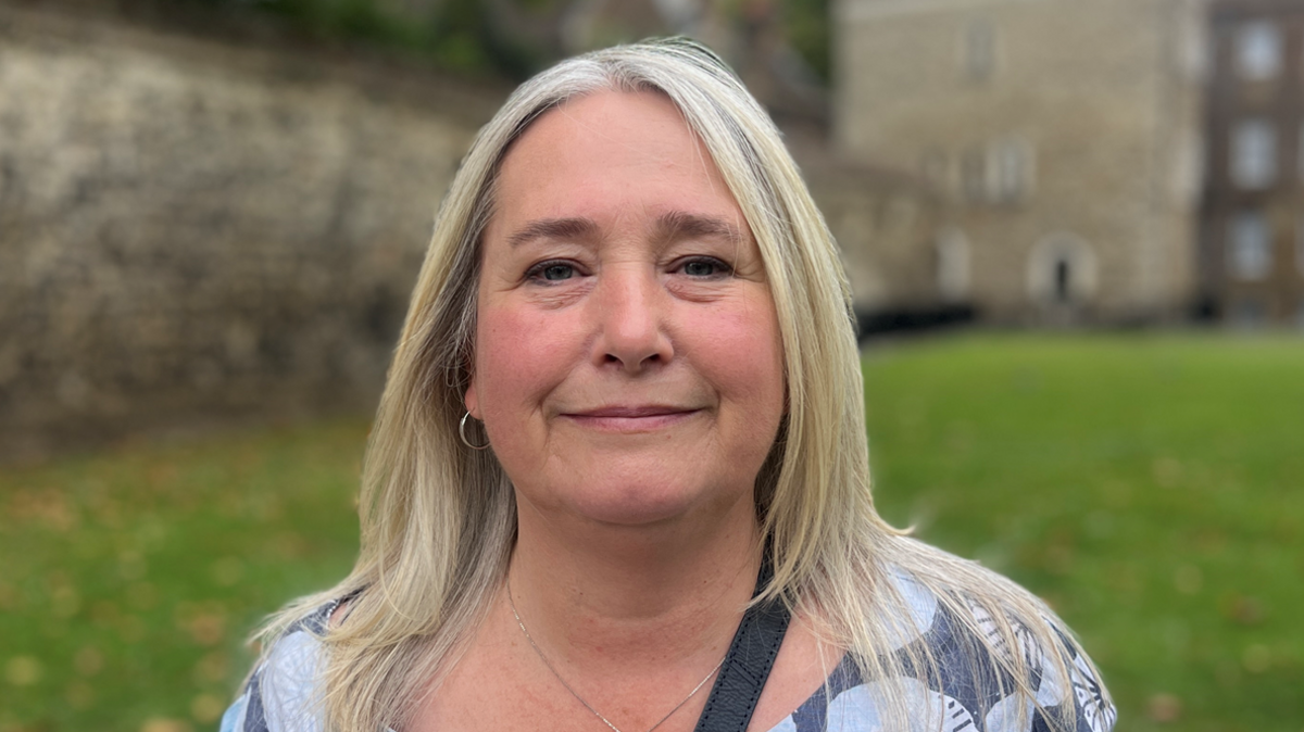 Claire is wearing a patterned top, she has long blonde hair and is standing on College Green, Westminster, being interviewed.