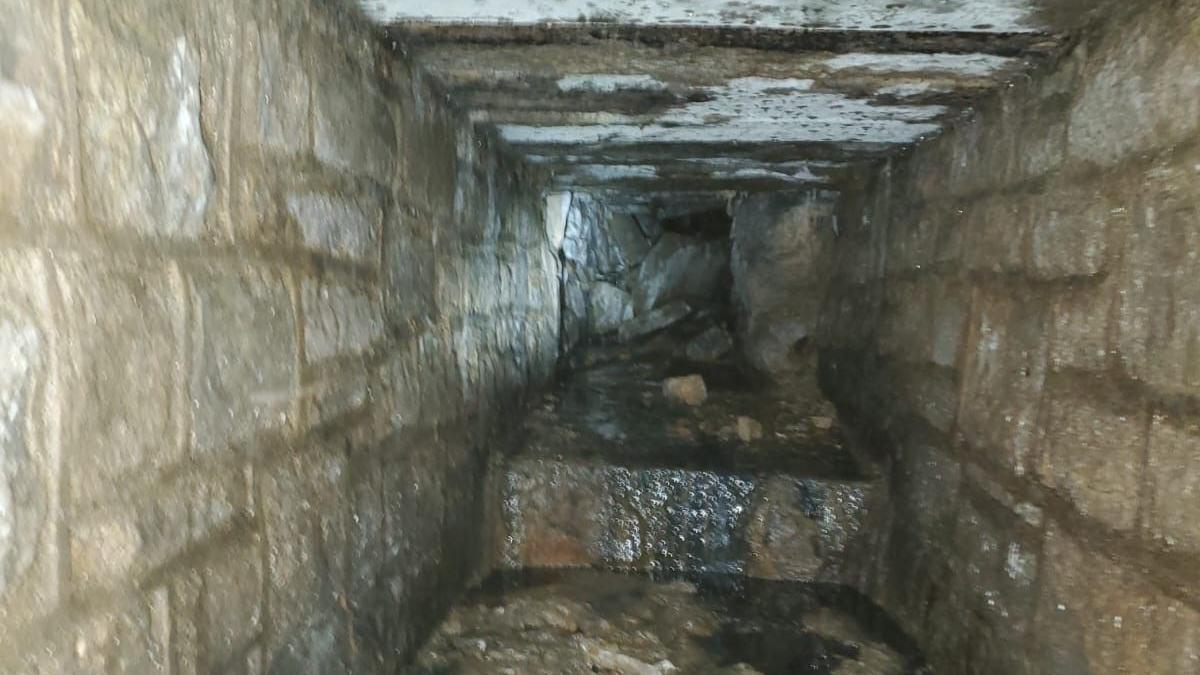 Inside the culvert, seemingly made from stone blocks joined by mortar, showing water trickling through the tunnel