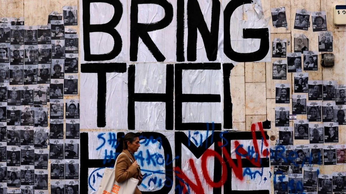 A woman walks past a wall of posters showing hostages taken to Gaza during the 7 October attacks, in Tel Aviv, Israel (24 January 2024)