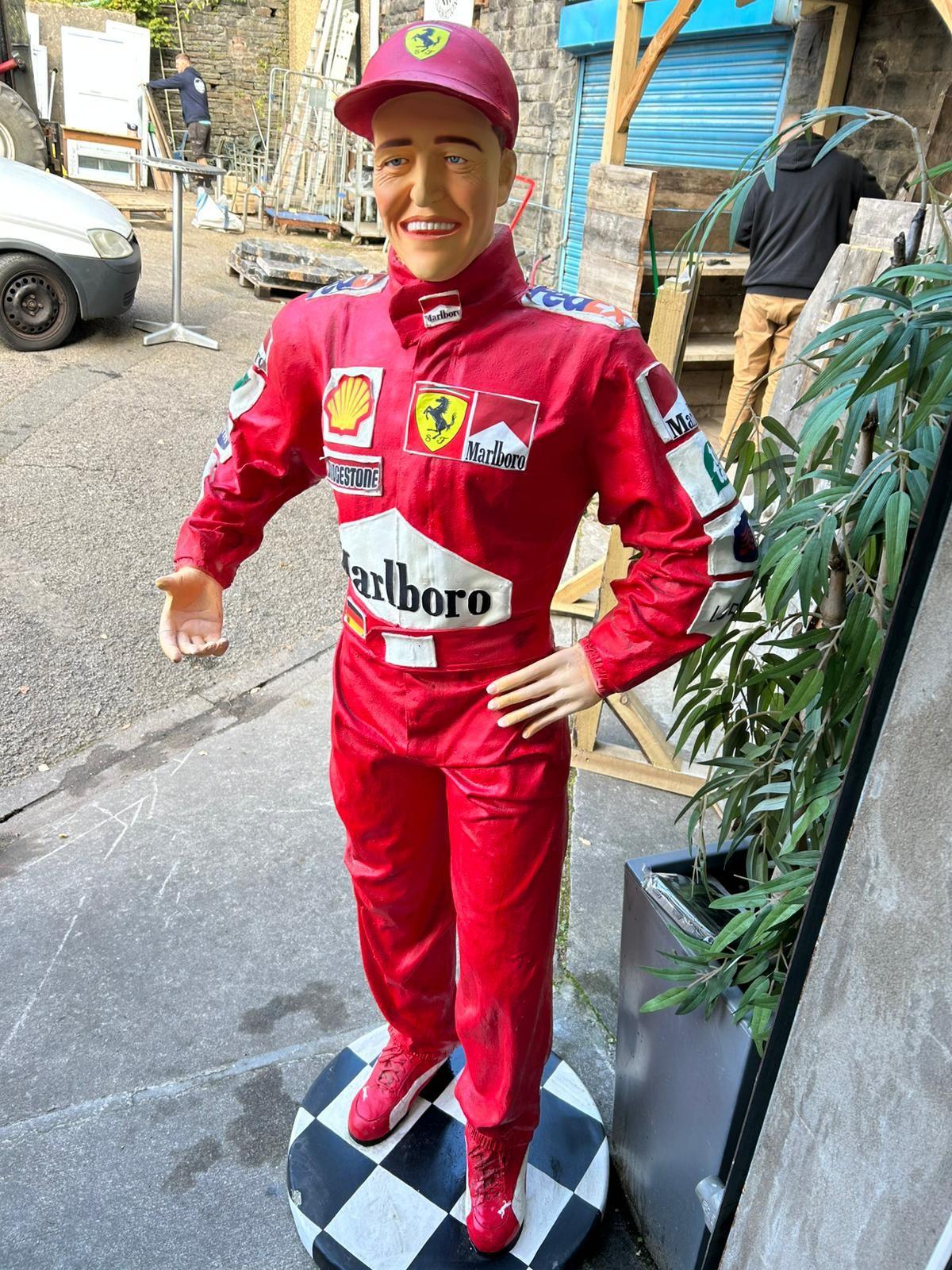 A statue of Michael Schumacher wearing a red race suit and hat