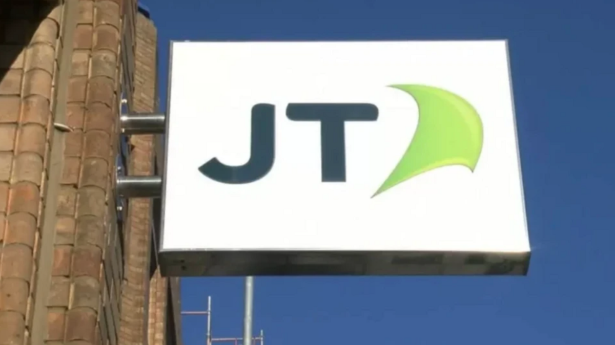 A close up of a JT Group sign against a blue sky.