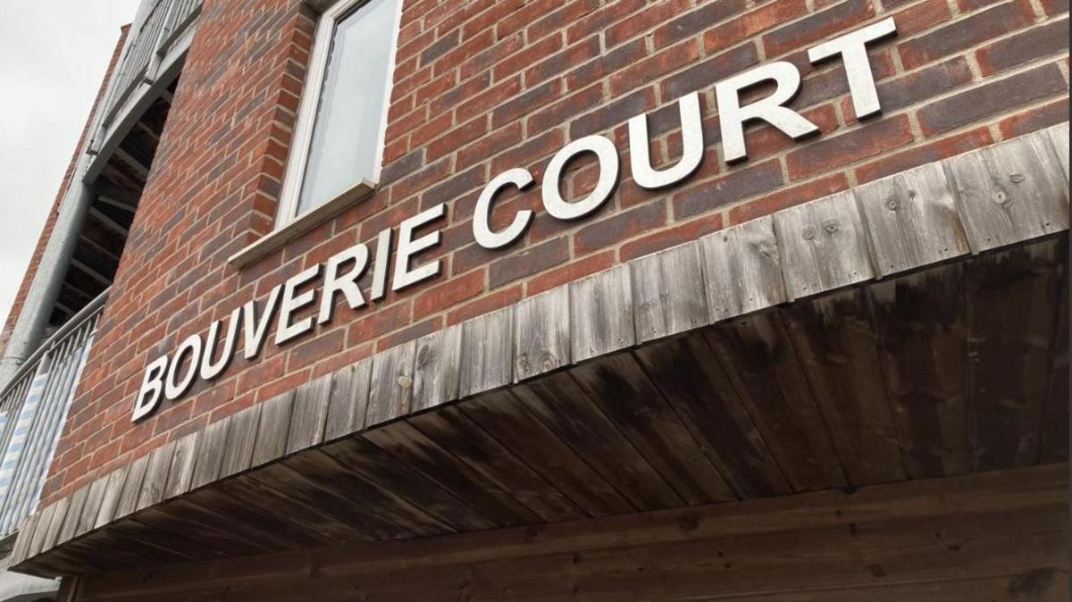 The exterior sign of Bouverie Court written in silver metal letters on a brick exterior wall.