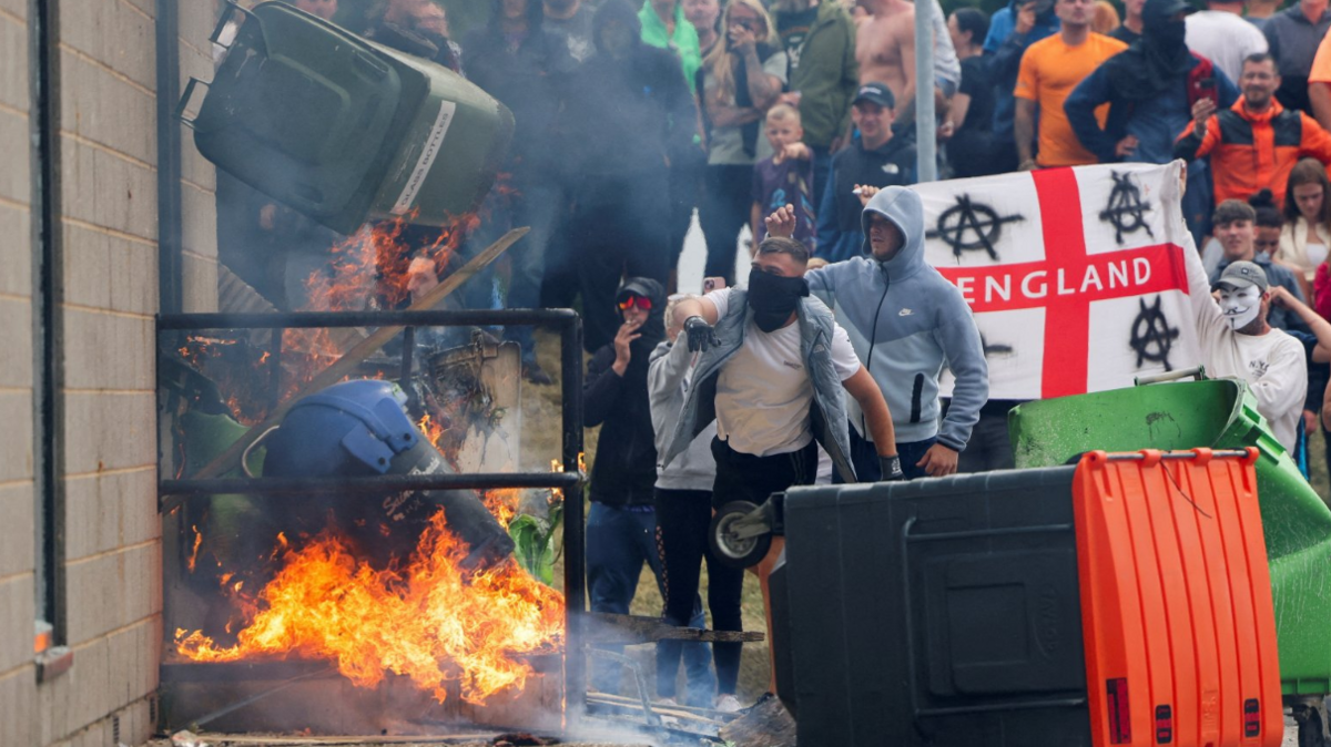 Protestors throw a garbage bin on fire outside a hotel in Rotherham