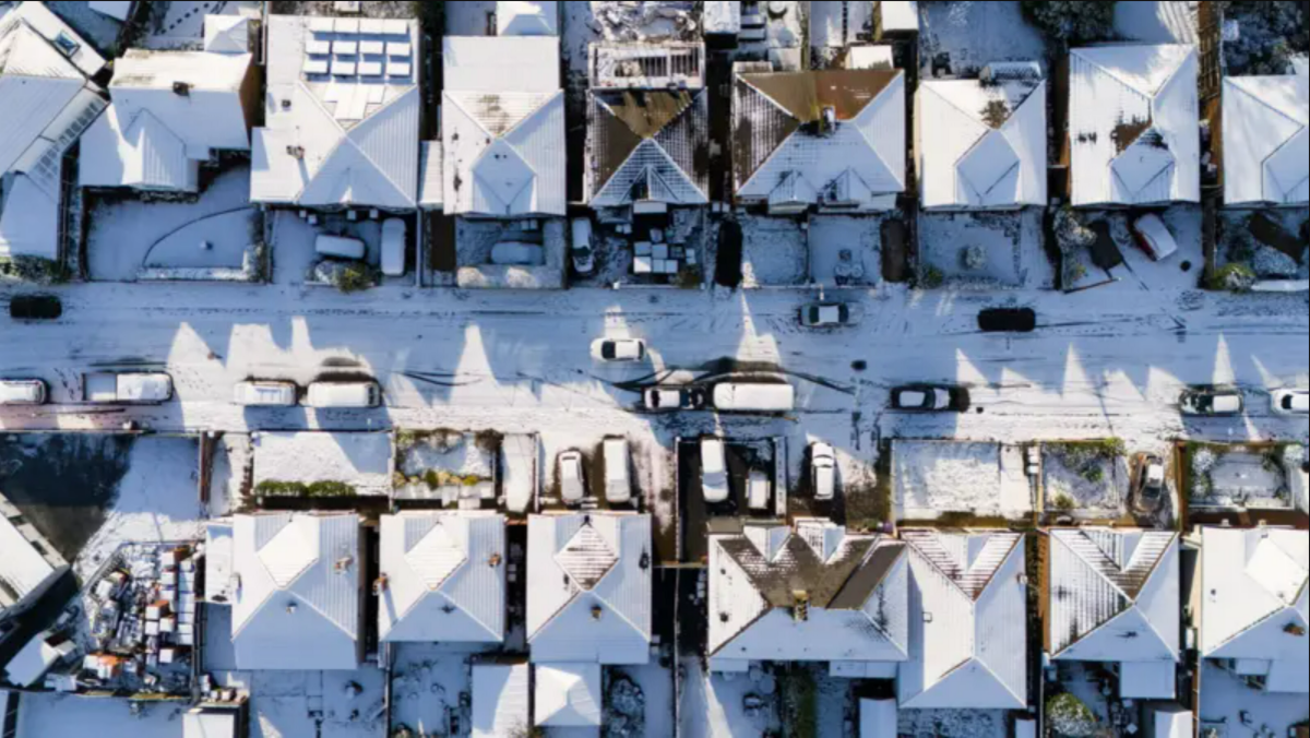 A drone shot showing snow on the roofs of houses 