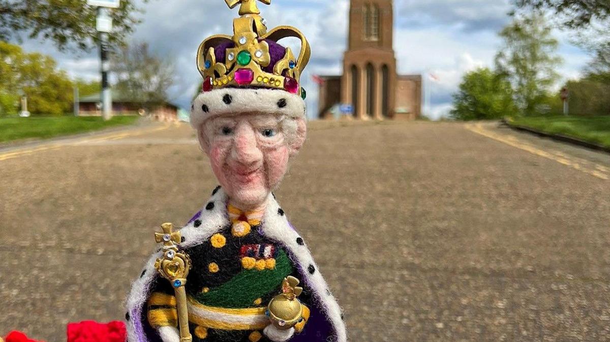 A postbox topper of King Charles III in front of Guildford Cathedral