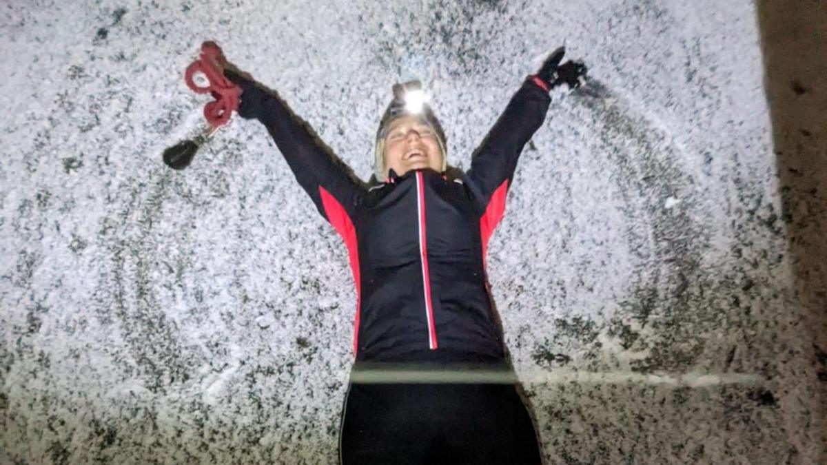 A woman in sports gear lying in the snow