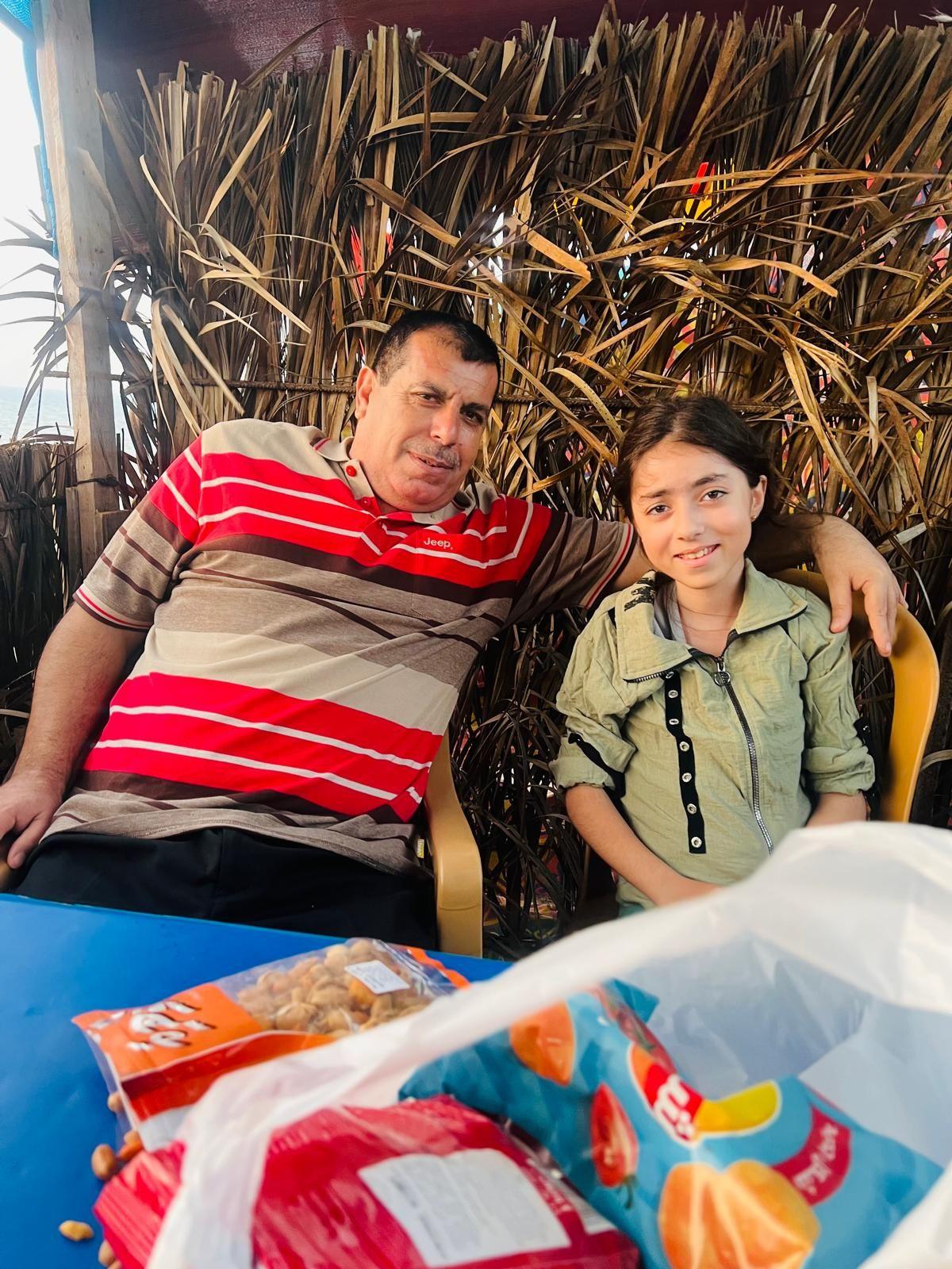 A man puts his arm around his daughter at a table 