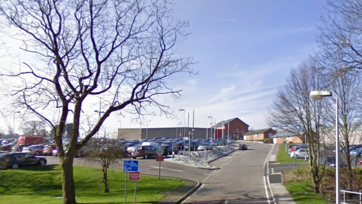 A google street view image of a the car park entrance to the HMP Lowdham Grange in Nottinghamshire, showing a car park with building in the background