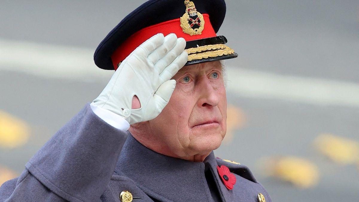 King Charles salutes the Cenotaph memorial. He is dressed in military uniform, with a white glove and black, red and gold hat