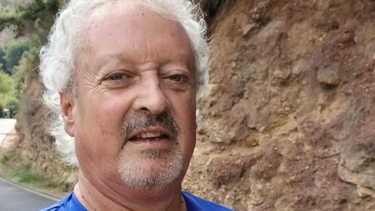 Selfie of Eddie Drury. He has longish grey hair and a goatee. There is a tone wall behind him and he is wearing a blue T-shirt.