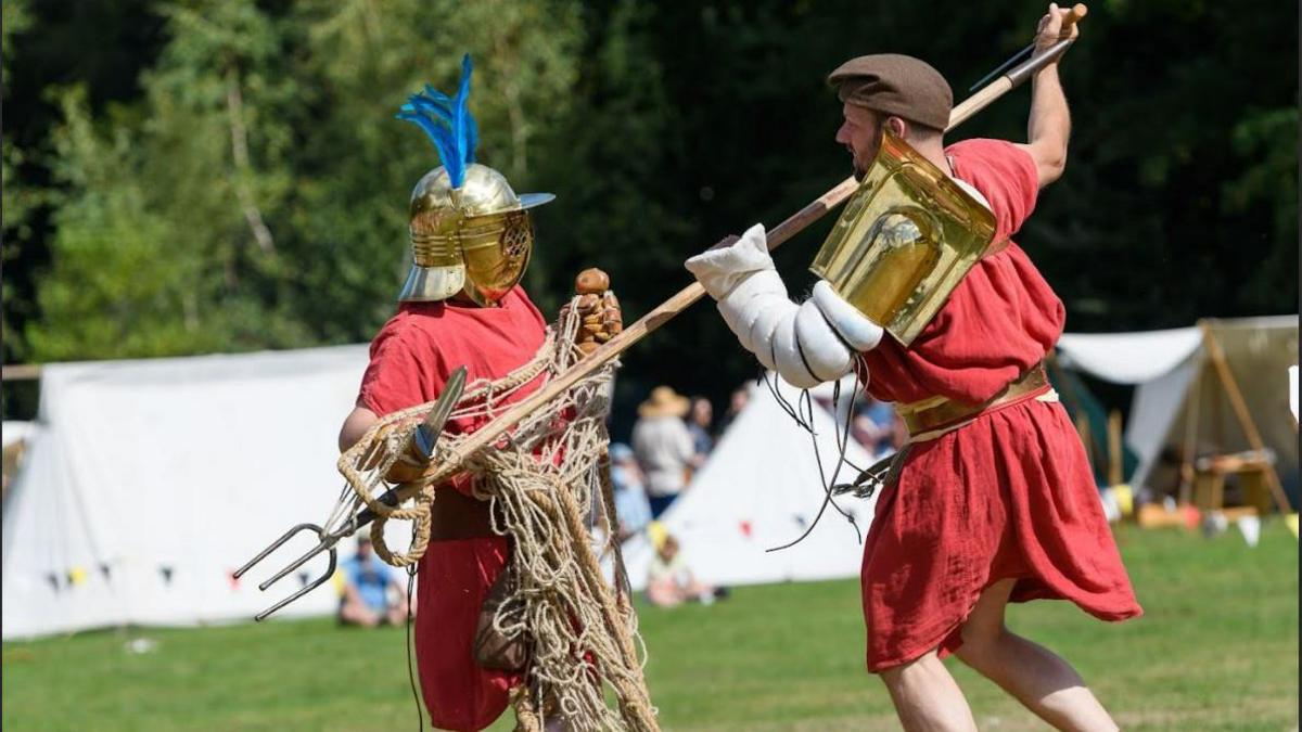 Two people dressed in medieval outfits are staging a fight