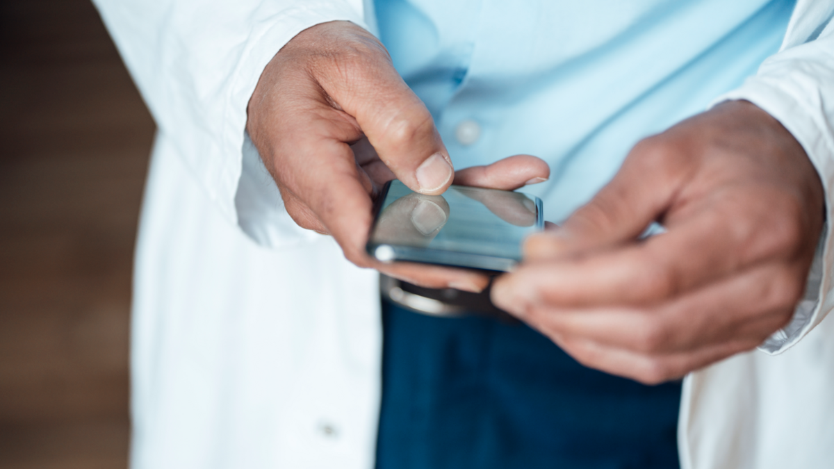 A close-up image of a doctor's hands, in which he holds a mobile phone