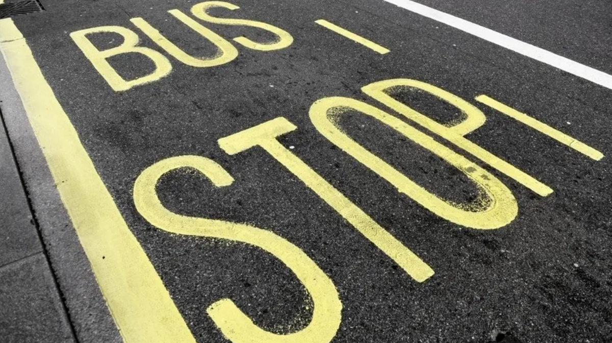 Yellow road markings saying "bus stop" on a tarmac road.